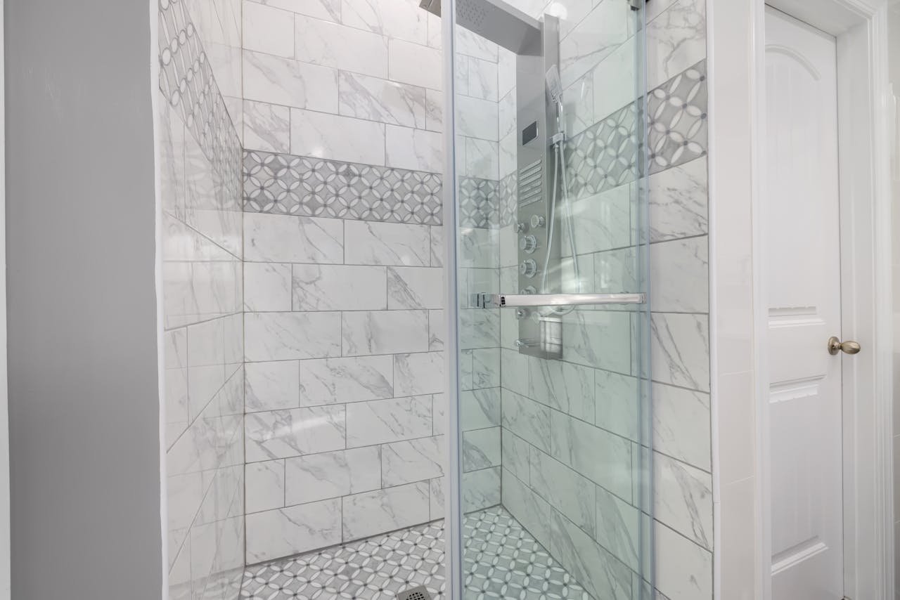 Sleek bathroom shower with marble tiles and glass door, showcasing modern interior design.